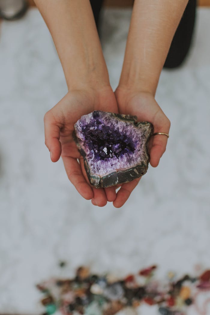 why-choose-us A close-up of hands holding a beautiful amethyst geode outdoors emphasizing its natural beauty.